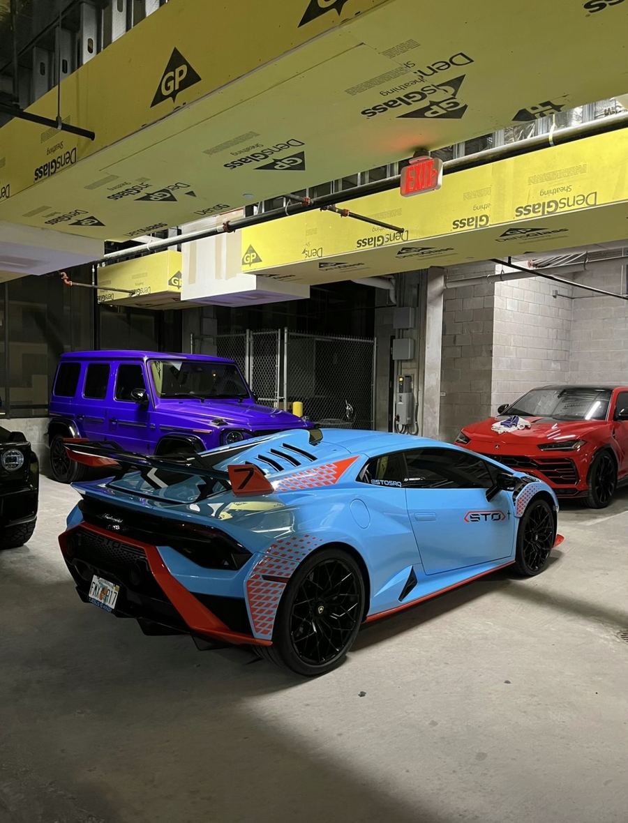 Gulf-liveried Lamborghini Huracan STO beside a Lamborghini Urus and Mercedes-AMG G-Class in a private Austin garage