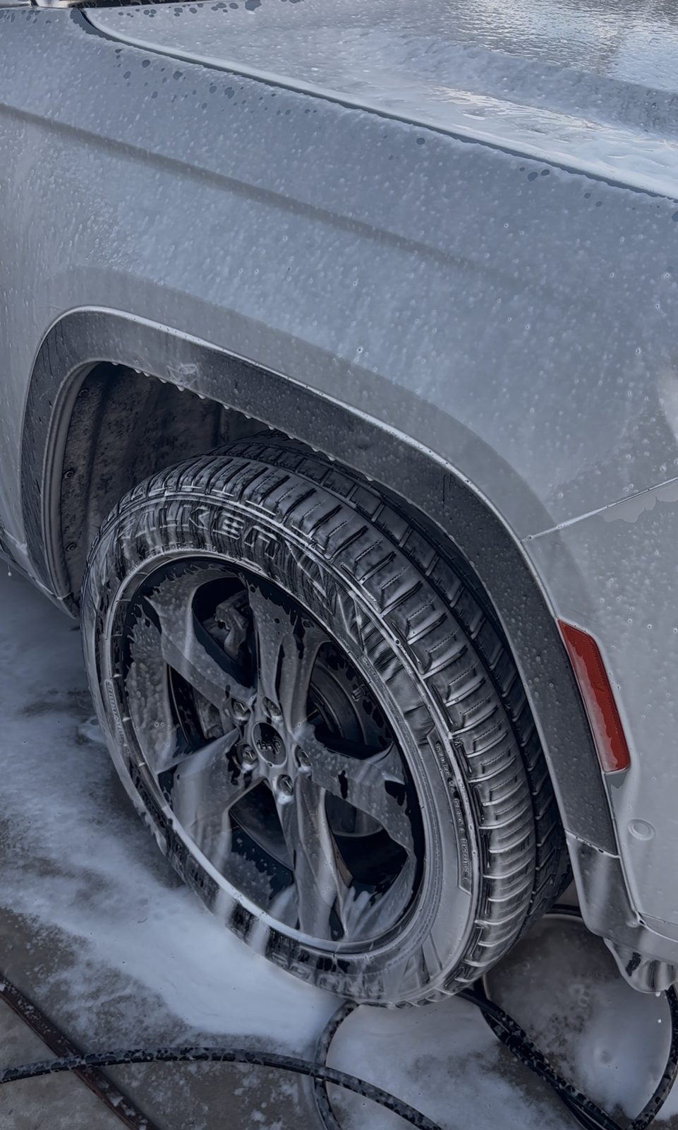 Wheel and lower bodywork covered in cleaning foam during a mobile exterior detail in Austin